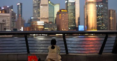 A woman sits on the Bund near Huangpu River as she looks at the financial district of Pudong, Shanghai, China, Sept. 27, 2024. (Reuters Photo)