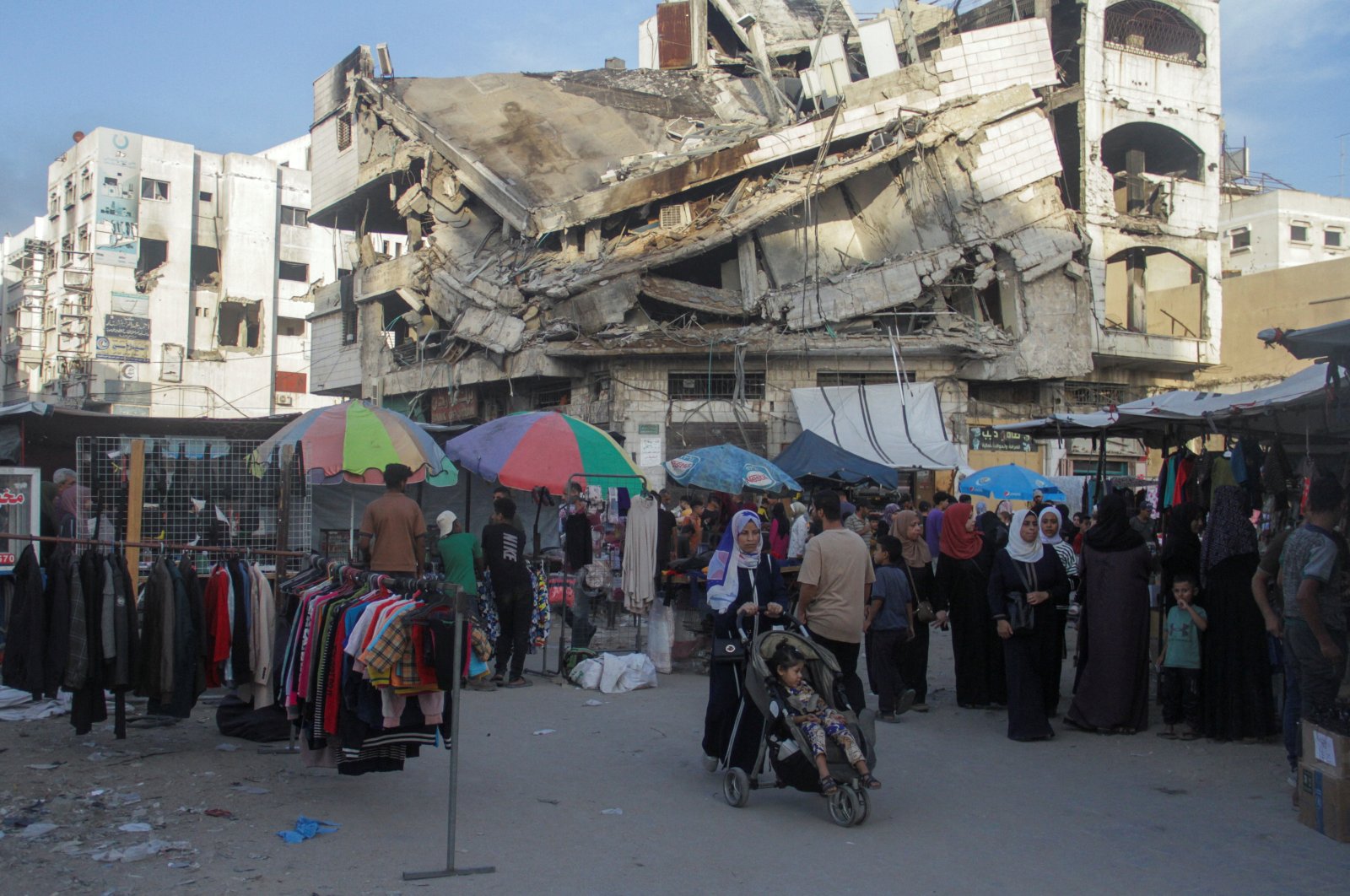 Palestinian people walk at a street market near the rubble of a building in Gaza City, Palestine, Oct. 13, 2024. (Reuters Photo)