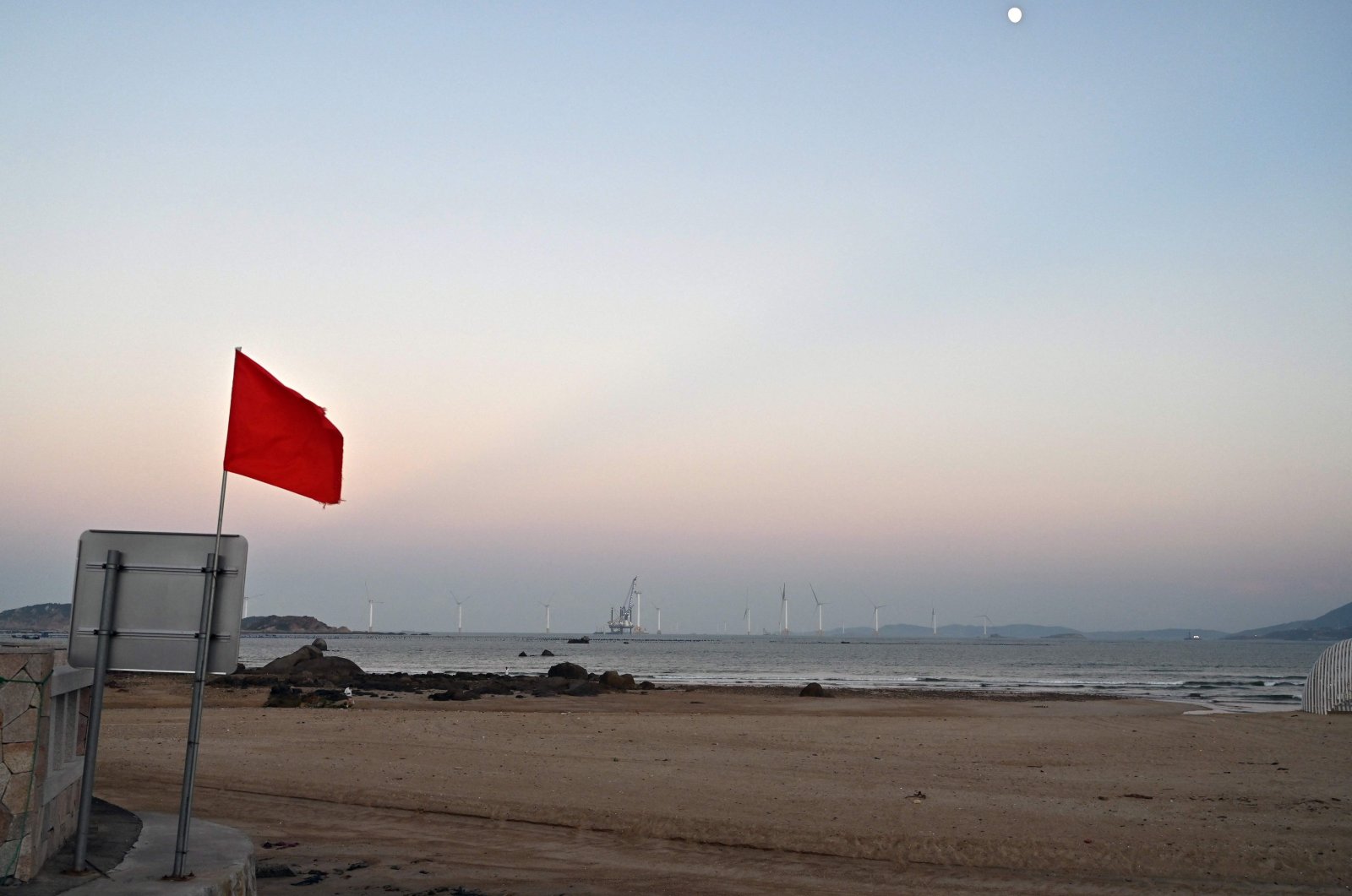 Wind turbines are seen past a red flag at a beach on Pingtan island, the closest point in China to Taiwan’s main island, Oct. 14, 2024. (AFP Photo)