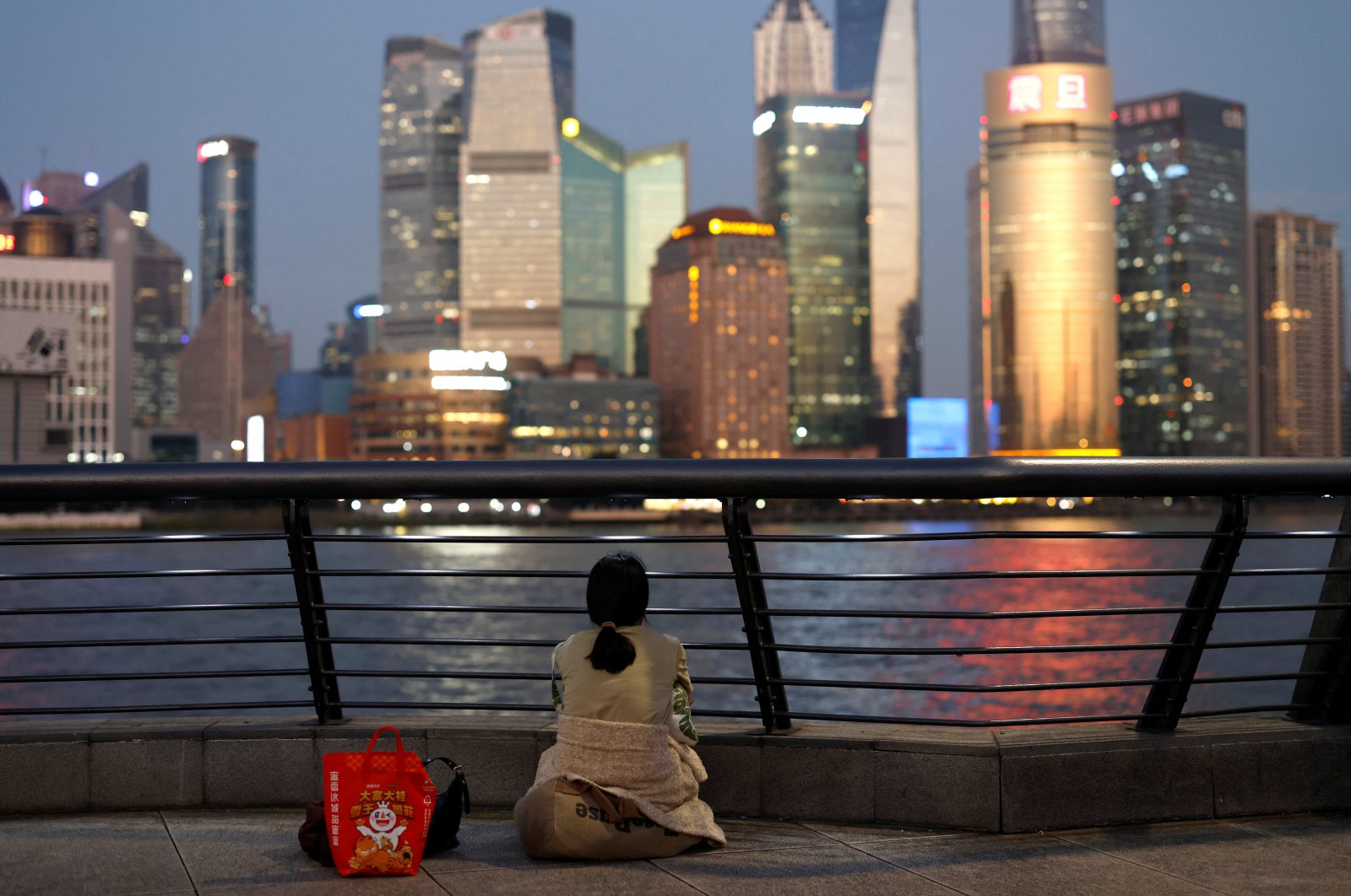 A woman sits on the Bund near Huangpu River as she looks at the financial district of Pudong, Shanghai, China, Sept. 27, 2024. (Reuters Photo)