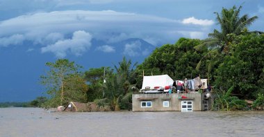 A resident hangs clothes atop their submerged house brought about from Tropical Storm Trami in Bula town, south of Manila, the Philippines, Oct. 26, 2024. (AFP Photo)
