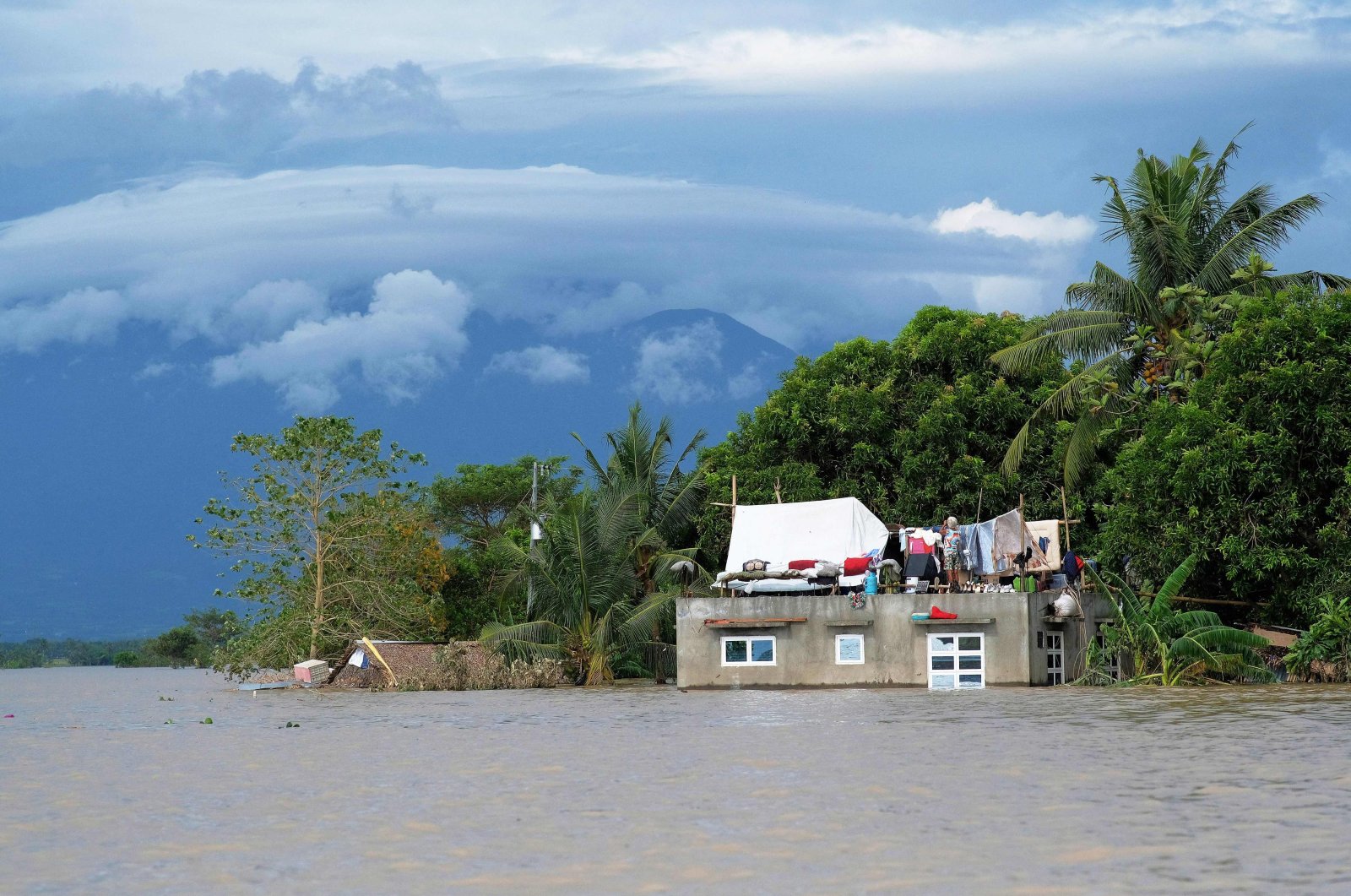 A resident hangs clothes atop their submerged house brought about from Tropical Storm Trami in Bula town, south of Manila, the Philippines, Oct. 26, 2024. (AFP Photo)