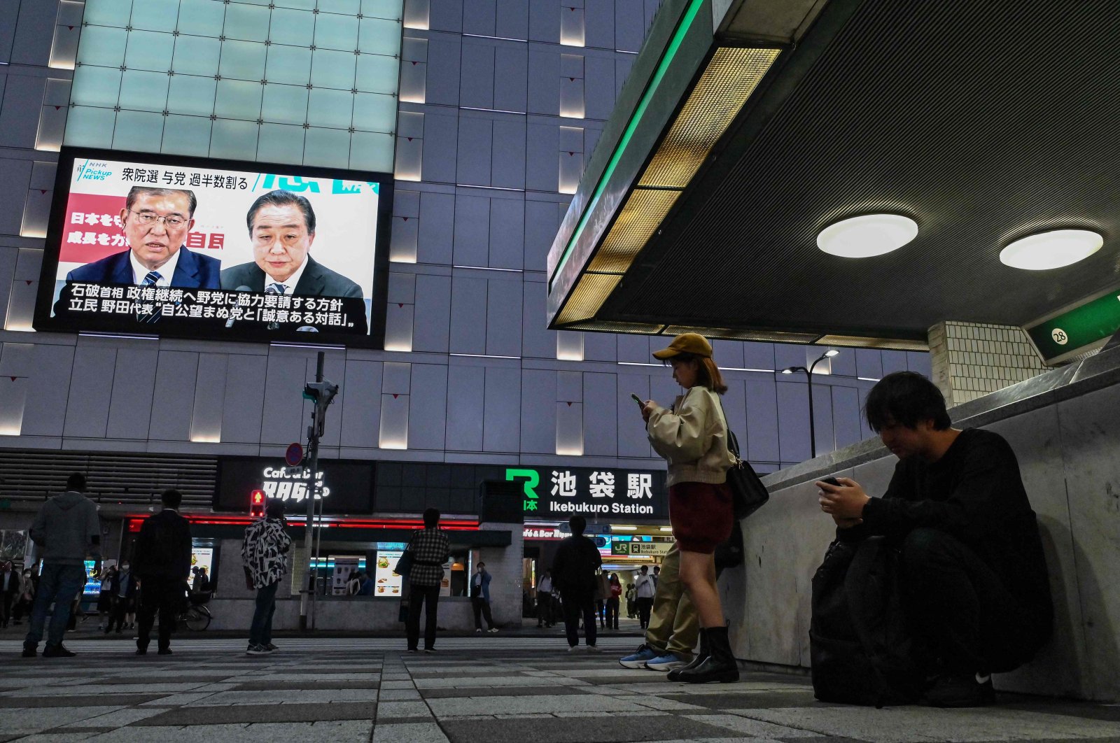 People stand outside Ikebukuro train station as images of Japan&#039;s Prime Minister Shigeru Ishiba (top L) and former premier and head of the opposition Constitutional Democratic Party (CDP), Yoshihiko Noda (top R) are broadcast during a news update on a large television screen after the general election in Tokyo, Japan, Oct. 28, 2024. (AFP Photo)