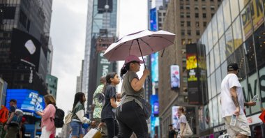 A pedestrian uses an umbrella to shield against the sun while passing through Times Square as temperatures rise, July 27, 2023, in New York. (AP File Photo)