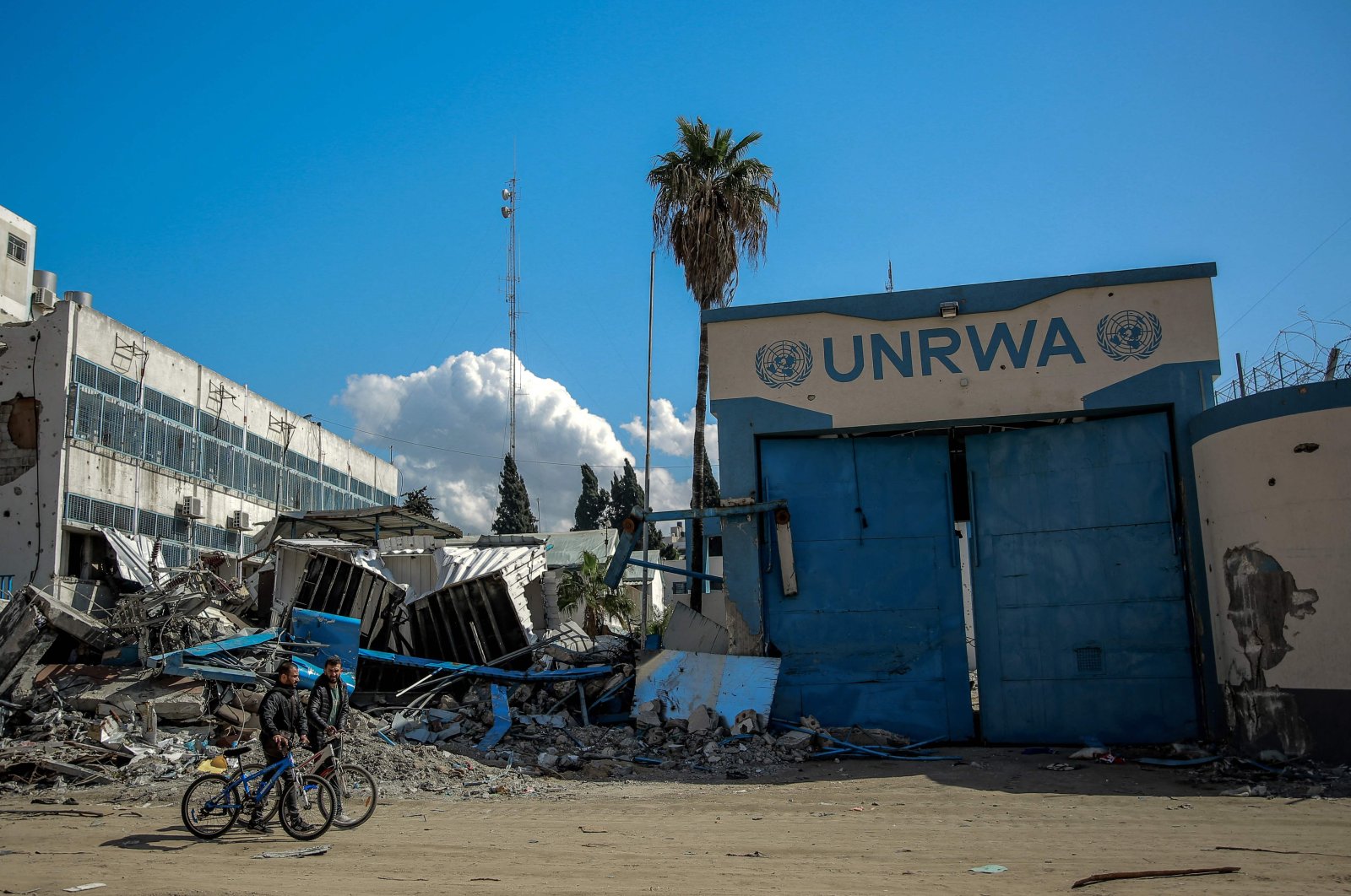 People walk past the damaged Gaza City headquarters of the United Nations Relief and Works Agency for Palestine Refugees (UNRWA), Gaza, Palestine, Feb. 15, 2024. (AFP Photo)