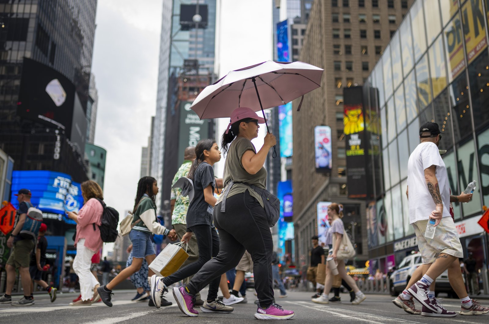 A pedestrian uses an umbrella to shield against the sun while passing through Times Square as temperatures rise, July 27, 2023, in New York. (AP File Photo)