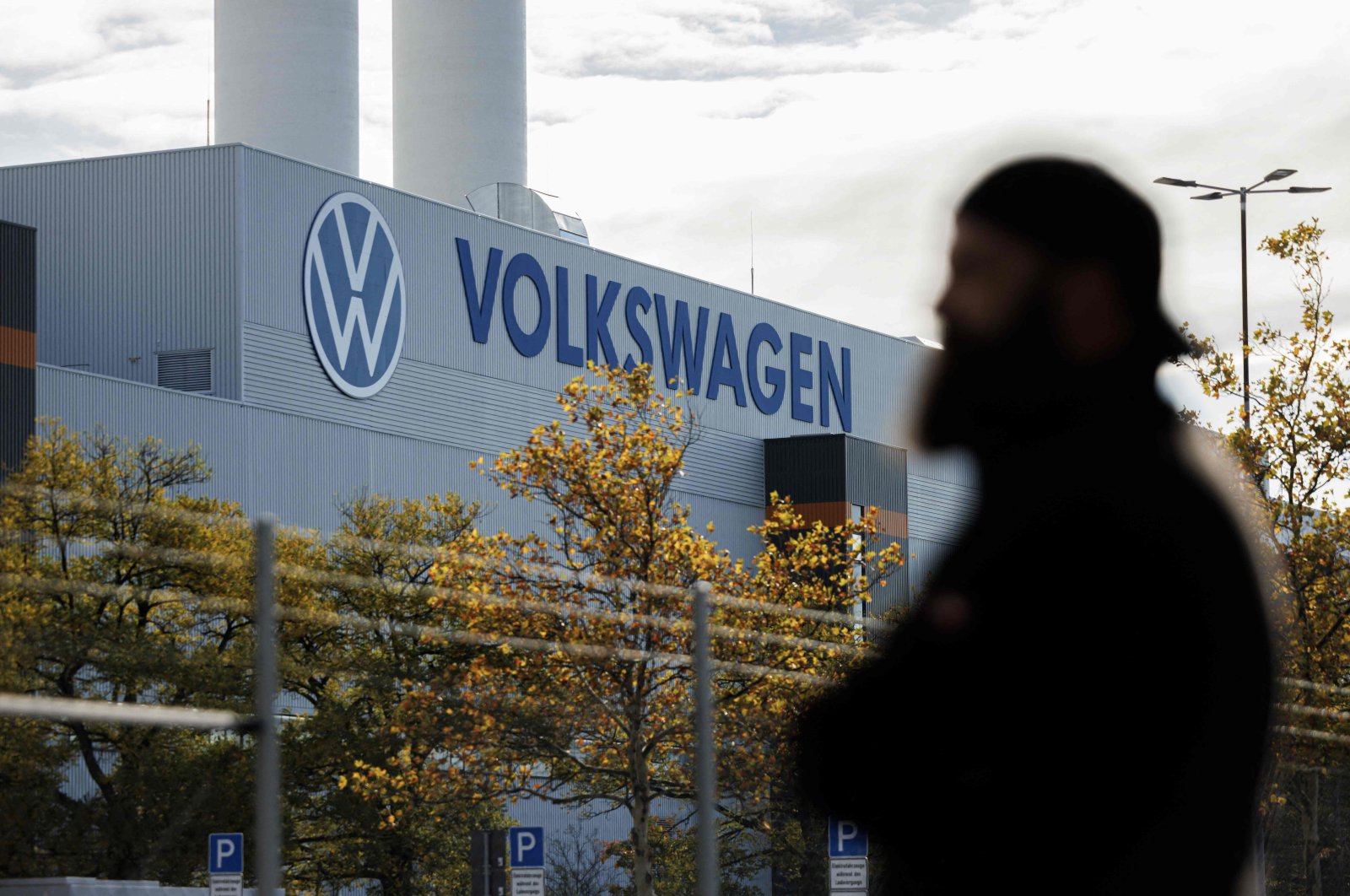 An employee of the Volkswagen plant in Zwickau stands next to the VW logo on the factory premises, Zwickau, eastern Germany, Oct. 28, 2024. (AFP Photo)