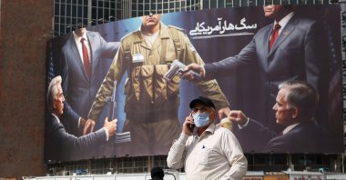 An elderly man walks past an anti-Israeli and U.S. billboard depicting an Israeli soldier receiving military supplies from the U.S. with the title "American rabid dog," at Tehran's Valiasr Square, Tehran, Iran, Oct. 28, 2024. (EPA Photo)
