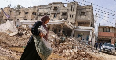 A woman walks past rubble as U.N. workers conduct rehabilitation works in the vicinity of the damaged U.N. agency for Palestinian refugees' (UNRWA) headquarters at the Nur Shams refugee camp east of Tulkarem, occupied West Bank, Palestine, Nov. 2, 2024. (AFP Photo)