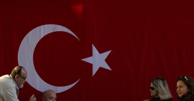 People are seen in front of a Turkish national flag hung on a wall to mark the 101st anniversary of the Turkish republic's foundation ahead of Republic Day, Istanbul, Türkiye, Oct. 28, 2024. (Reuters Photo)