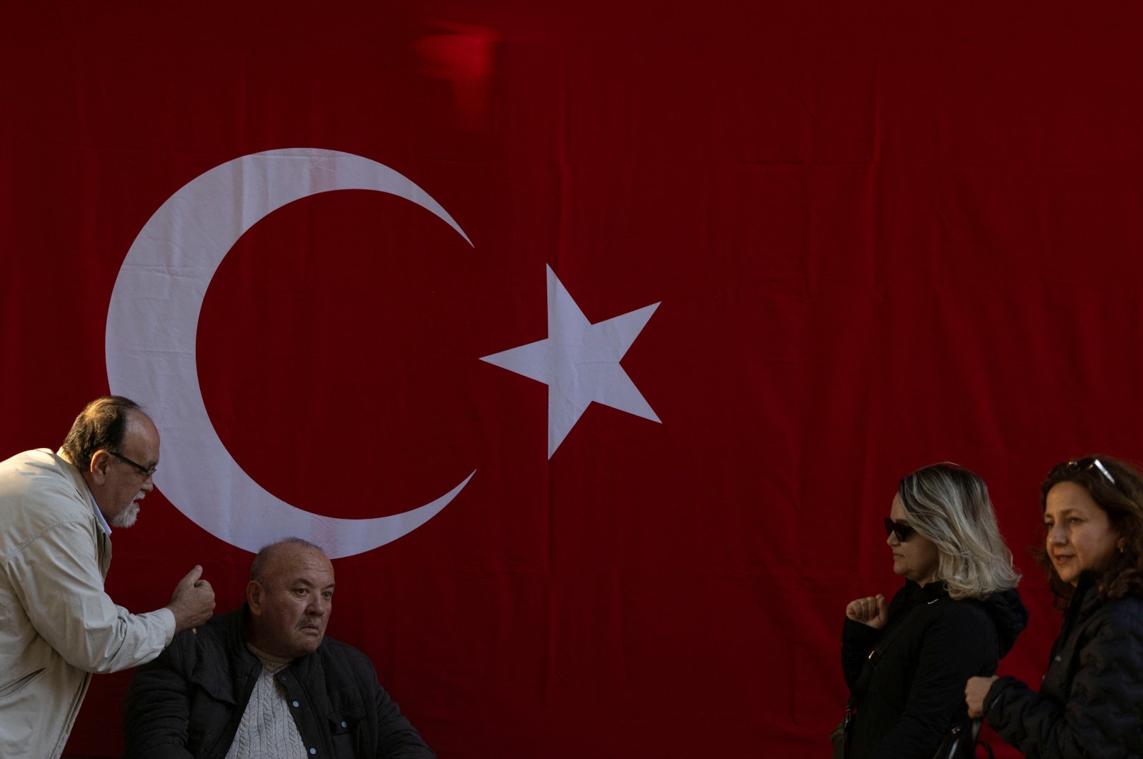 People are seen in front of a Turkish national flag hung on a wall to mark the 101st anniversary of the Turkish republic&#039;s foundation ahead of Republic Day, Istanbul, Türkiye, Oct. 28, 2024. (Reuters Photo)