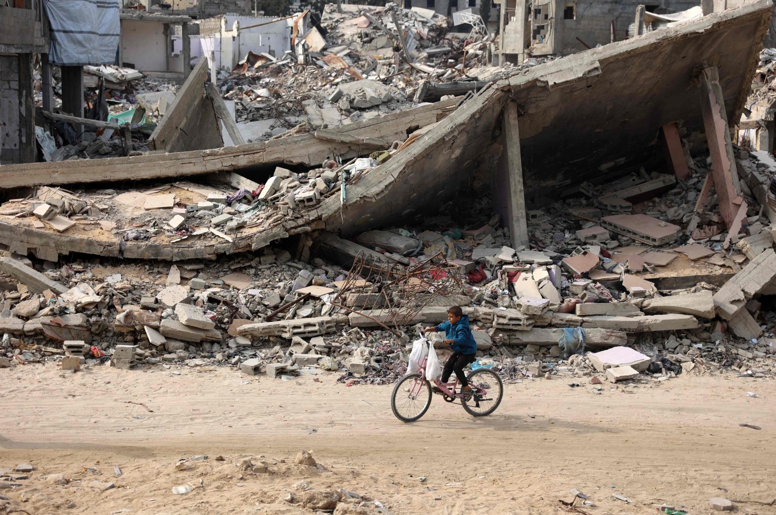 A Palestinian child rides his bicycle past a levelled building in Gaza City, Gaza Strip, Palestine, Nov. 2, 2024. (AFP Photo) 