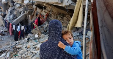A Palestinian woman carries her child near the ruins of a house destroyed in the Israeli attack, in Khan Younis, Gaza, Palestine, Nov. 4, 2024. (Reuters Photo) 