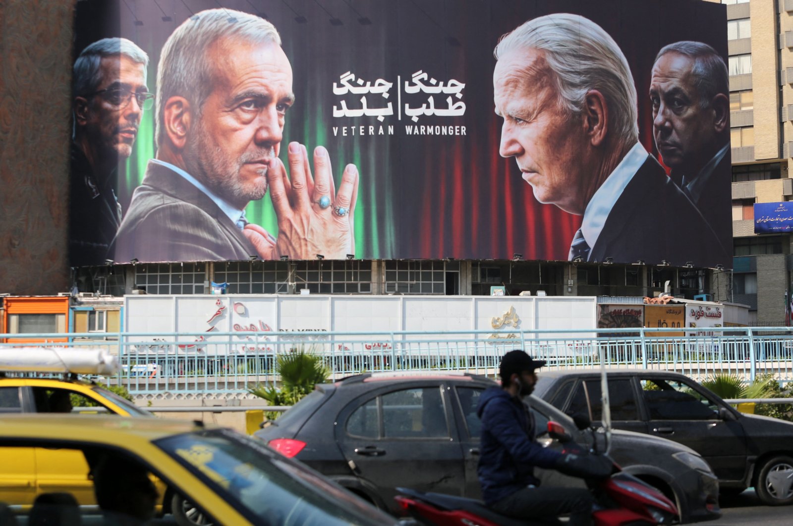 Commuters drive past a billboard bearing pictures of Iran&#039;s President Masoud Pezeshkian (2-L), armed forces chief of staff Maj. Gen. Mohammad Bagheri (L), U.S. President Joe Biden (2-R) and Israeli Prime Minister Benjamin Netanyahu in Vali-Asr square, Tehran, Iran, Oct. 27, 2024. (AFP Photo)