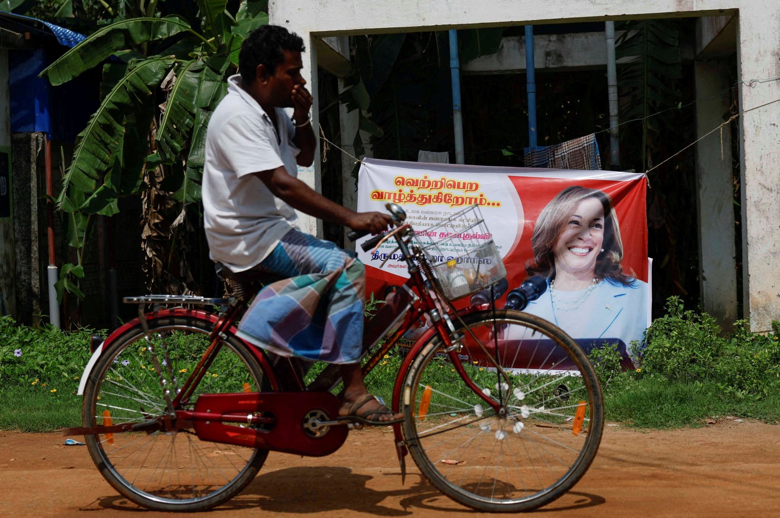 A man cycles past a poster of Democratic presidential nominee U.S. Vice President Kamala Harris in Thulasendrapuram, Tamil Nadu, India, Nov. 4, 2024. (Reuters Photo)