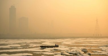 A man steers his boat across river Yamuna laden with toxic foam as smog engulfs New Delhi, India, Nov. 6, 2024. (AFP Photo)