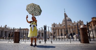 A woman takes a selfie as she shelters from the sun with an umbrella near St. Peter's Square during a heatwave in Rome, Italy, July 11, 2024. (Reuters Photo)