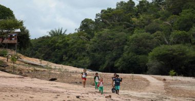Children walk on a sandbank on their way to school in the Santo Antonio Community in Novo Airao, Amazonas state, northern Brazil, Oct. 1, 2024. (AFP Photo)