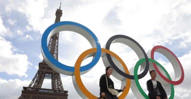 Tourists sit on the Olympic rings displayed in front of the Eiffel Tower in Paris, Sept. 27, 2024. (AFP Photo)