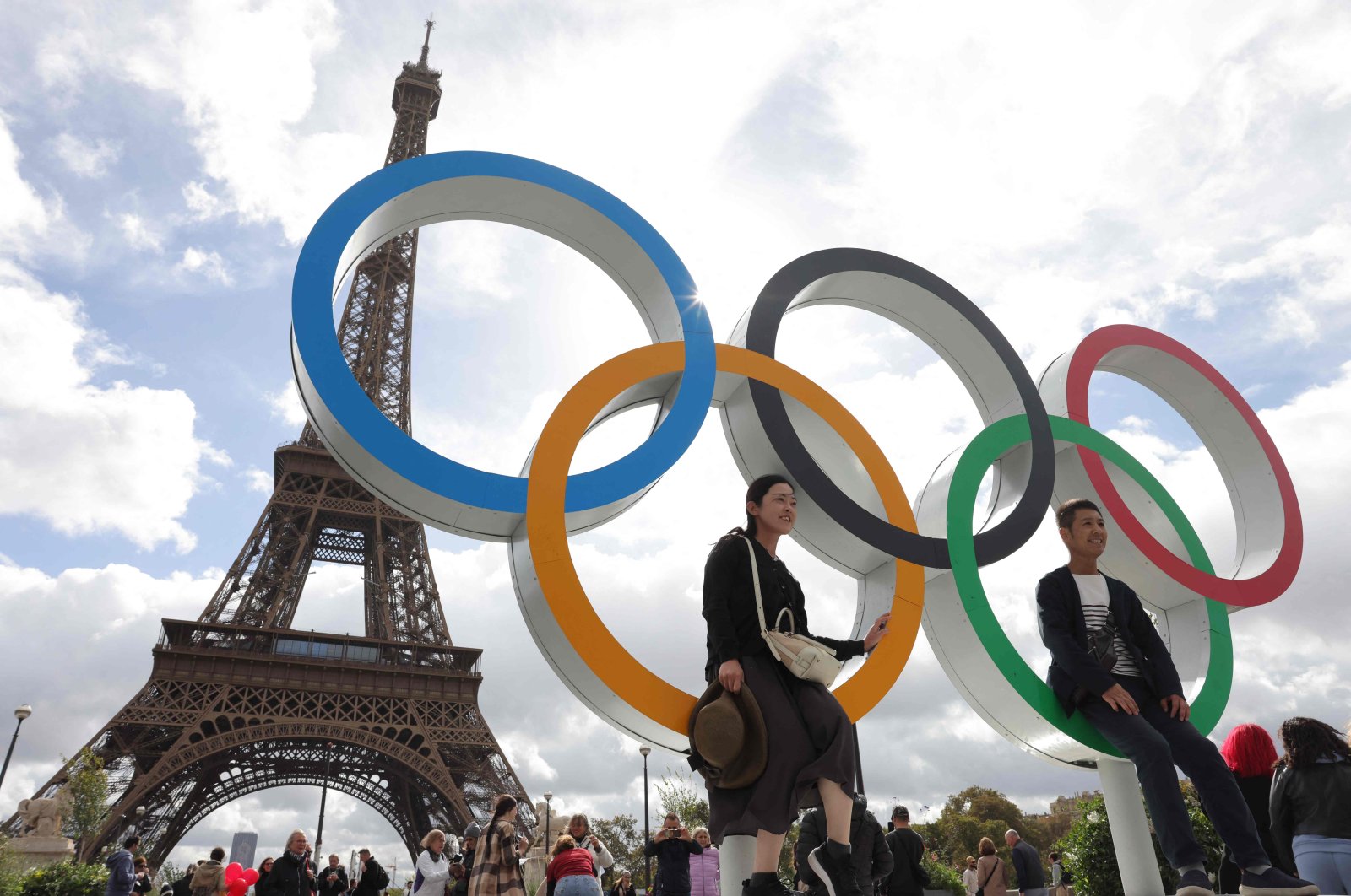 Tourists sit on the Olympic rings displayed in front of the Eiffel Tower in Paris, Sept. 27, 2024. (AFP Photo)