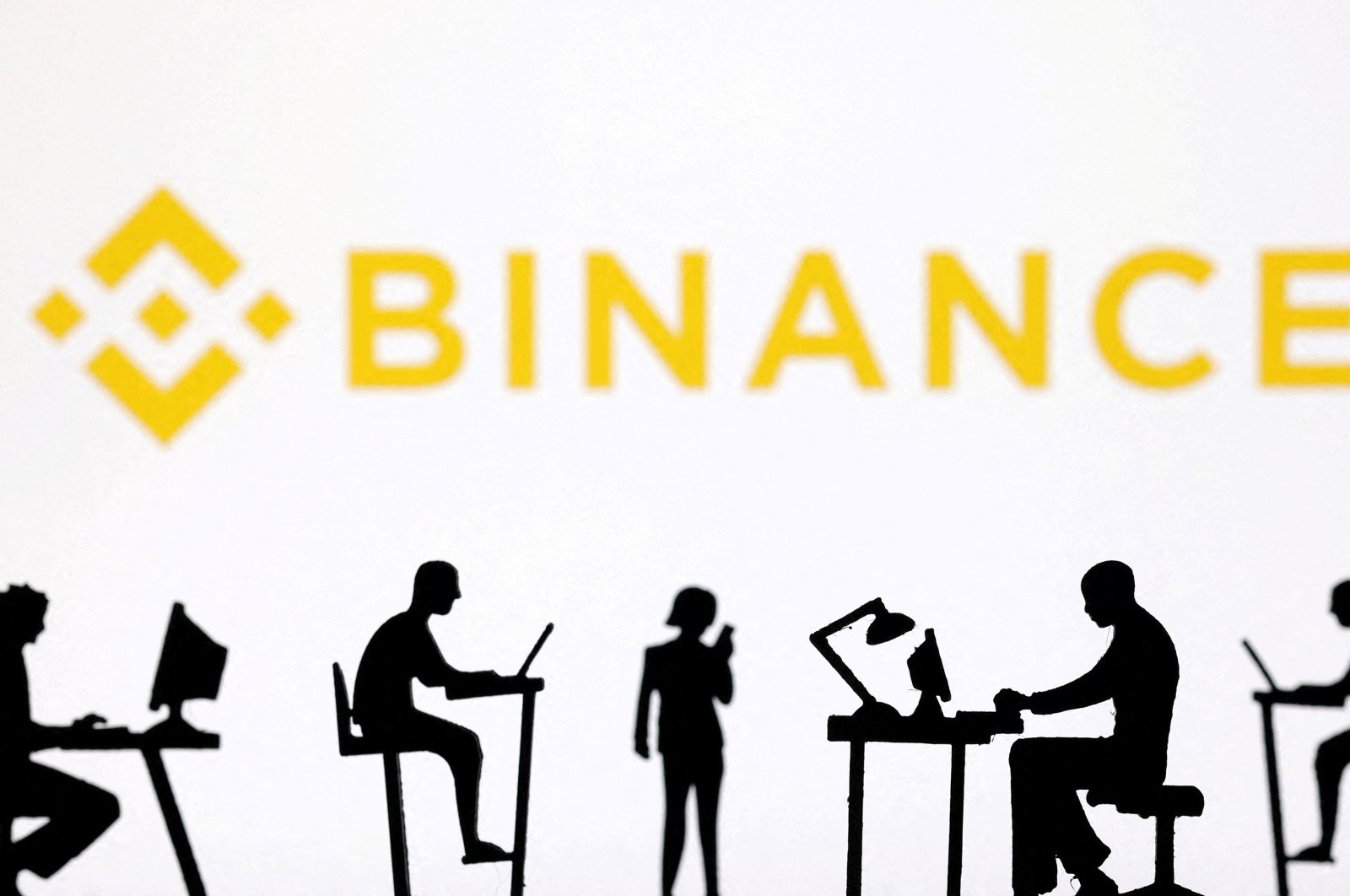 Figurines with computers and smartphones are seen in front of the Binance logo in this illustration, Feb. 19, 2024. (Reuters Photo)