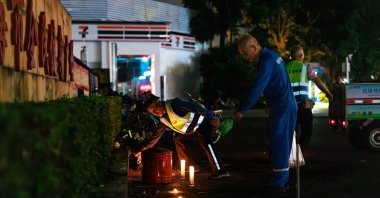 Workers remove flowers and candles left by mourners for the victims of a car ramming incident, at the entrance to the Zhuhai Sports Center, Zhuhai, China, Nov. 12, 2024. (EPA Photo)