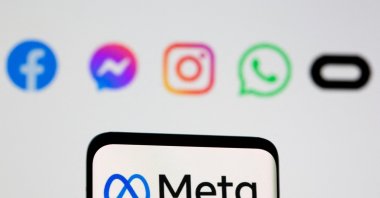 Facebook&#039;s new rebrand logo Meta is seen on smartpone in front of displayed logo of Facebook, Messenger, Intagram, Whatsapp, Oculus in this illustration picture, Oct. 28, 2021. (Reuters Photo)