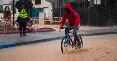 A man rides a bicycle down a flooded street, Campanillas, Malaga, Spain, Nov. 13, 2024. (AFP Photo)