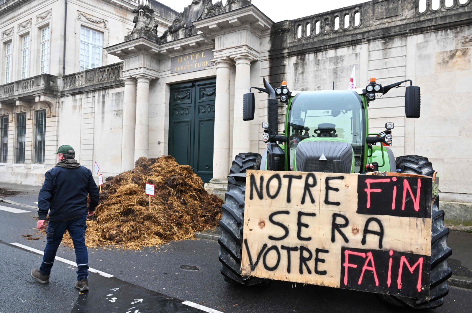 A farmer walks past a sign reading &quot;Our end will be your hunger&quot; on a tractor during a demonstration organized by French farmer union FDSEA 51, Chalons-en-Champagne, northeastern France, Oct. 18, 2024. (AFP Photo)