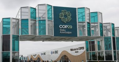People walk past the entrance of the venue of the United Nations climate change conference COP29, Baku, Azerbaijan, Nov. 11, 2024. (Reuters Photo)