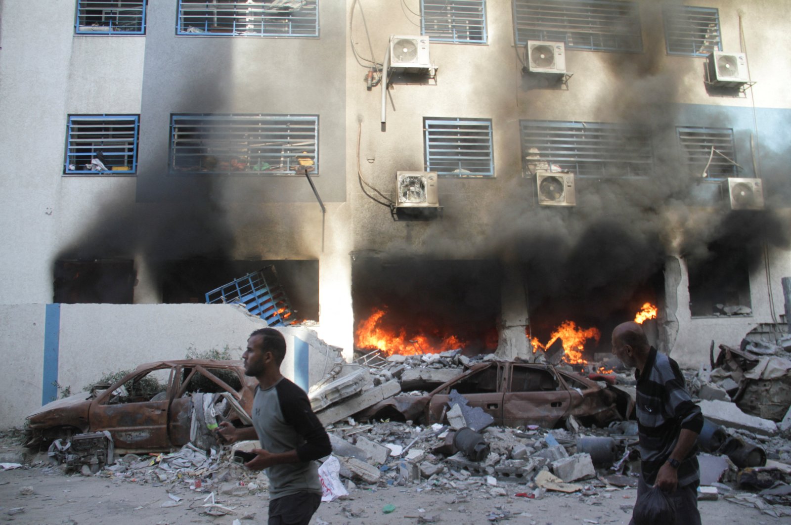 Palestinians walk next to A fire at a school sheltering displaced people, after it was hit by an Israeli strike, Gaza City, Palestine, Nov. 14, 2024. (Reuters Photo)