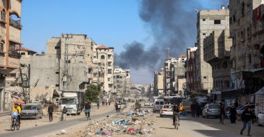 Smoke from Israeli bombardment billows as people walk at al-Jalaa street in Gaza City, Palestine, Nov. 14, 2024, (AFP Photo)