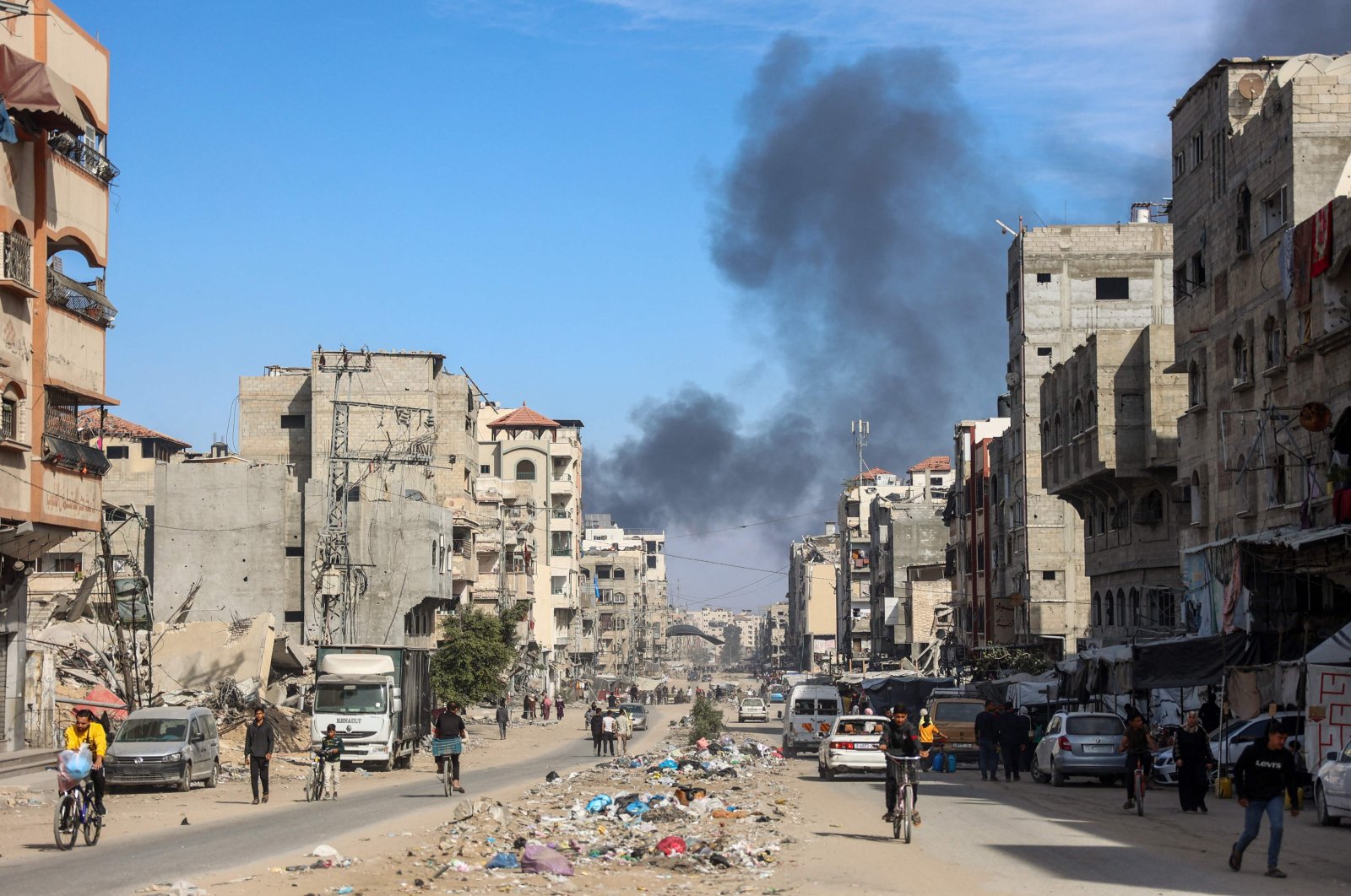 Smoke from Israeli bombardment billows as people walk at al-Jalaa street in Gaza City, Palestine, Nov. 14, 2024, (AFP Photo)