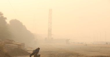A man rests on his bike amid heavy smog on the outskirts of New Delhi, India, Nov. 15, 2024. (IHA Photo)