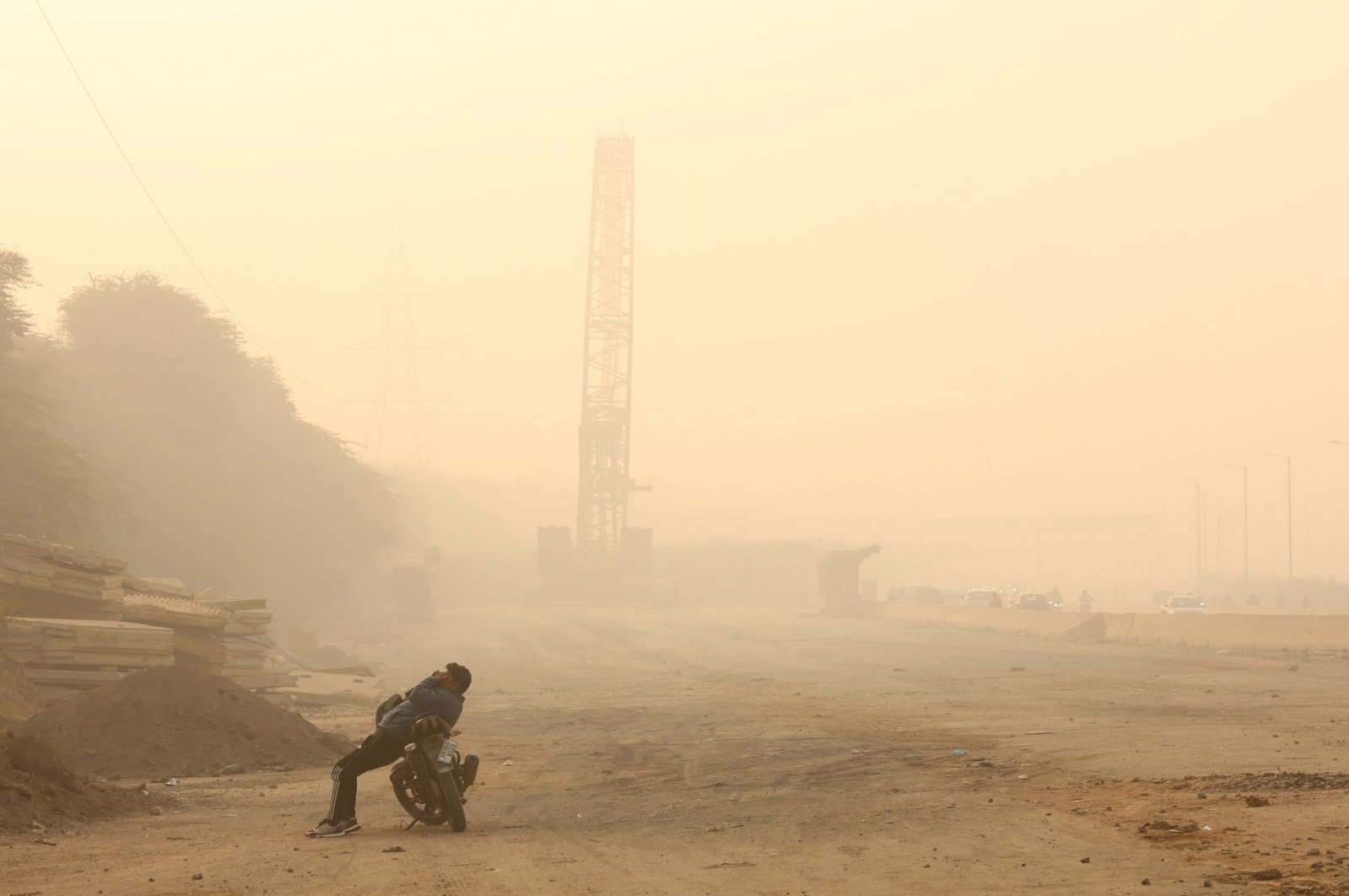 A man rests on his bike amid heavy smog on the outskirts of New Delhi, India, Nov. 15, 2024. (IHA Photo)