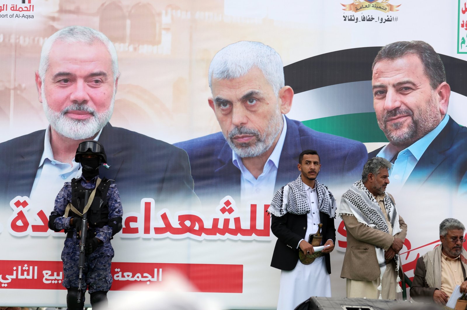 People stand in front of a banner showing (R-L) late Hamas leaders Saleh al-Arouri, Yahya Sinwar and Ismail Haniyeh during a rally, Sanaa, Yemen, Oct. 25, 2024. (EPA Photo)