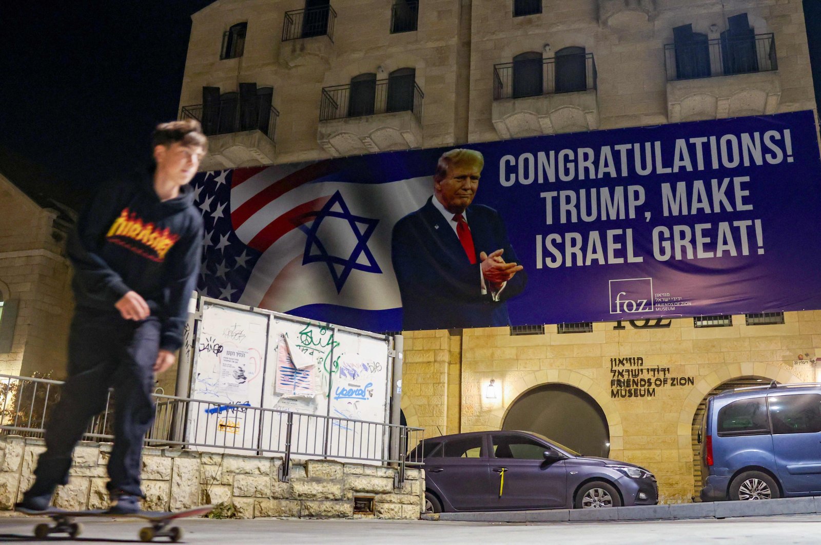 A youth skateboards under a banner congratulating U.S. President-elect Donald Trump on winning the U.S. presidential election, Jerusalem, Israel, Nov. 7, 2024. (AFP Photo)