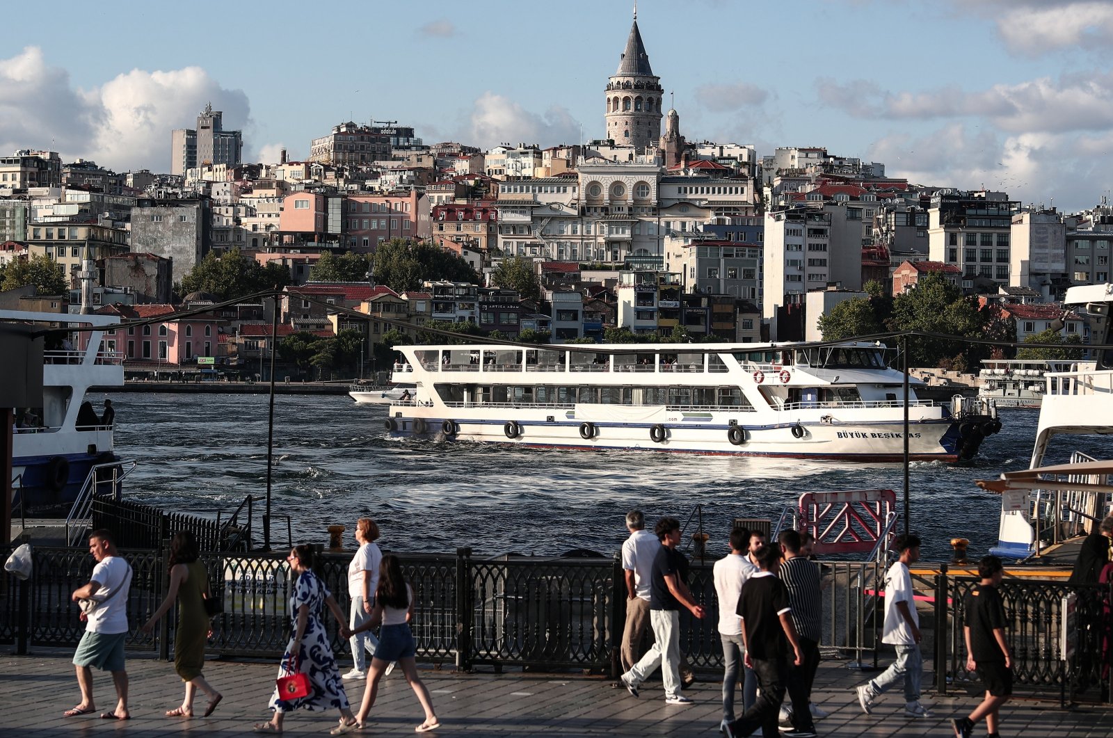 People walk along the Golden Horn as the Galata Tower is seen in the background, Istanbul, Türkiye, July 31, 2024. (EPA Photo)