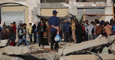 A Palestinian man holds a plastic bag with fresh bread and waits among the debris of buildings destroyed by Israeli airstrikes, Khan Younis, southern Gaza, Palestine, Nov. 20, 2024. (AFP Photo)