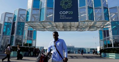 A man with a suitcase walks near the entrance of the COP29 United Nations climate change conference venue, Baku, Azerbaijan, Nov. 22, 2024. (Reuters Photo)