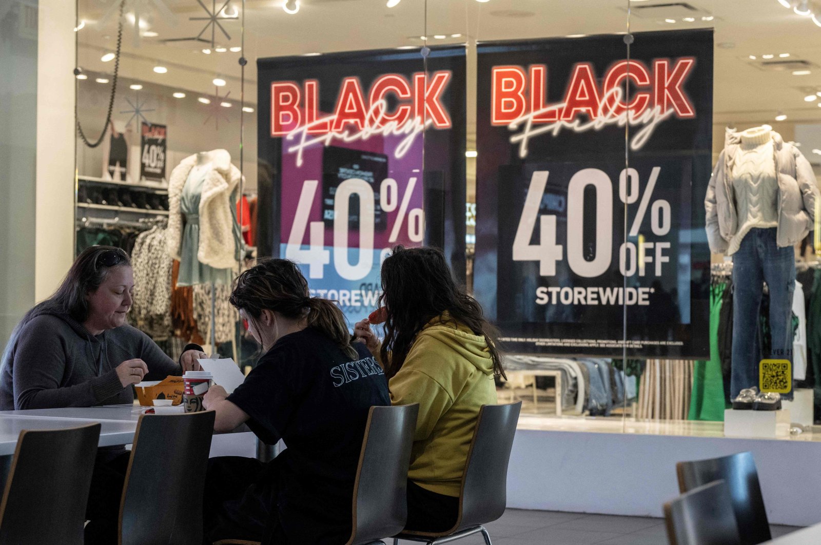 A family eats lunch near a store advertising a Black Friday sale at the Pentagon City Mall in Arlington, Virginia, U.S., Nov. 22, 2023. (AFP Photo)