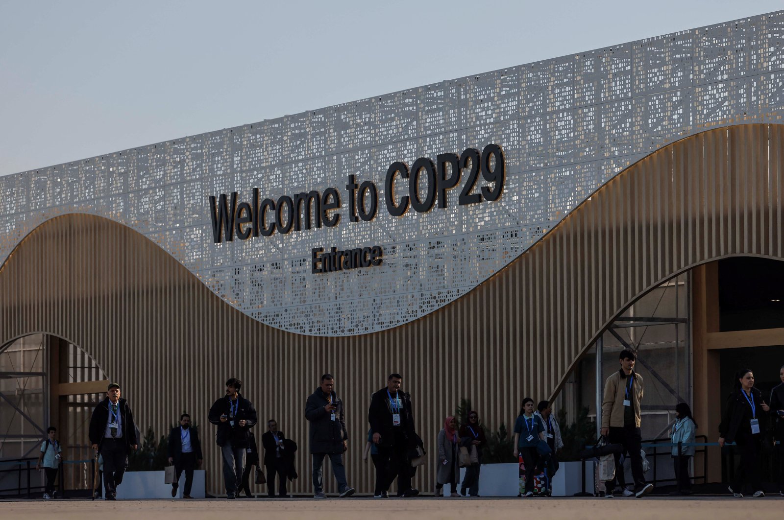 People walk next to the COP29 United Nations climate change conference pavilion, in Baku, Azerbaijan, Nov. 22, 2024. (Reuters Photo)