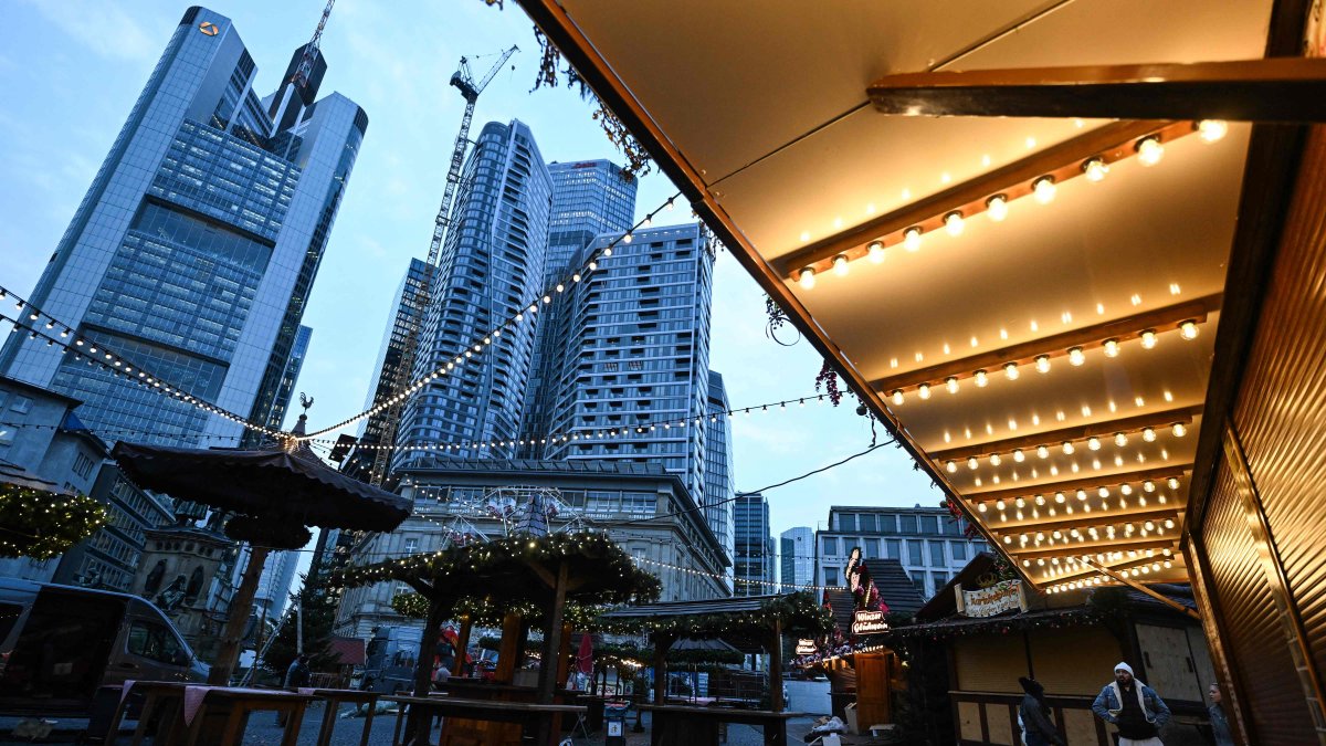 People walk through Christmas-themed booths in front of the banking district skyline, central Frankfurt, Germany, Nov. 21, 2024. (AFP Photo)