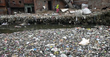 Residents walk next to a canal filled with plastic garbage, New Delhi, India, Sept. 8, 2024. (AFP Photo)