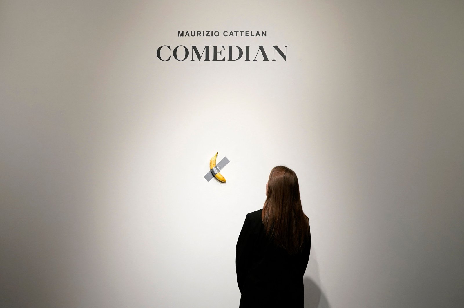 A woman looks at Italian visual artist Maurizio Cattelan’s duct-taped Banana entitled &quot;Comedian,&quot; during a press preview at Sotheby&#039;s in New York, U.S., Oct. 25, 2024. (AFP Photo)