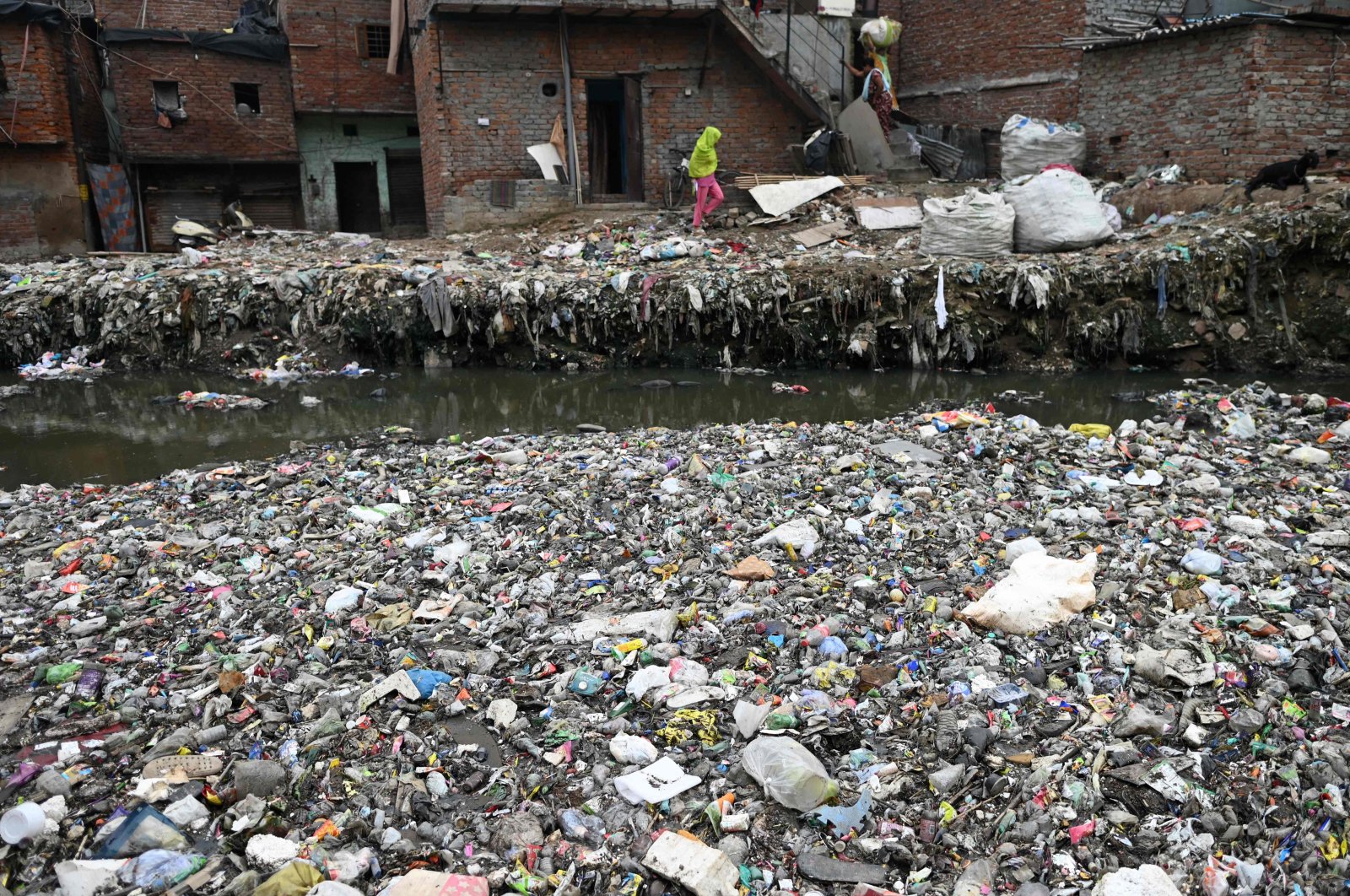 Residents walk next to a canal filled with plastic garbage, New Delhi, India, Sept. 8, 2024. (AFP Photo)