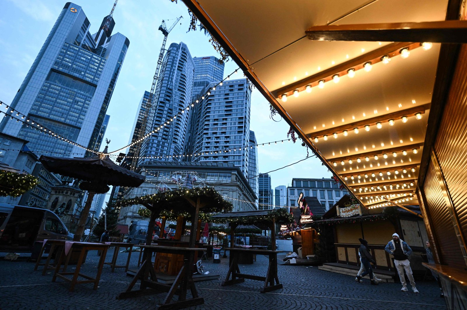 People walk through Christmas-themed booths in front of the banking district skyline, central Frankfurt, Germany, Nov. 21, 2024. (AFP Photo)