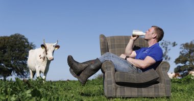 This undated handout photo shows Bryce Cunningham, farmer and owner of Mossgiel Organic Farm near Mauchline, as he poses drinking milk in a field with some of his herd of Ayrshire cows at Mossgiel Organic Farm, Mauchline, Scotland, U.K. (AP Photo)