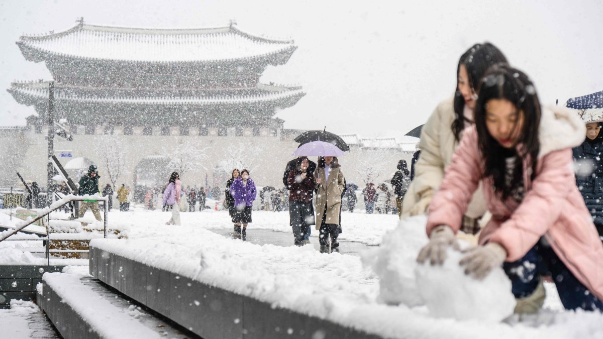 Pedestrians walk in front of the Gyeongbokgung Palace amid heavy snowfall in central Seoul, South Korea, Nov. 27, 2024. (AFP Photo)