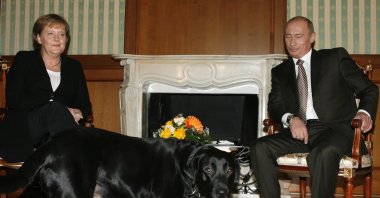 German Chancellor Angela Merkel and Russian President Vladimir Putin look on as Putin&#039;s dog Cony walks past during the meeting in Putin&#039;s residence in the Russian Black Sea resort of Sochi, Jan. 21, 2007. (AP File Photo)
